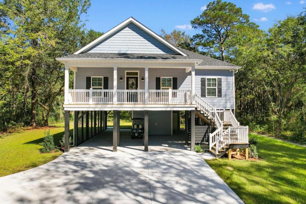 a white house with a porch and a deck at Munn Hub Live the Dream 4 Bdrm Home with Pool in Pawleys Island