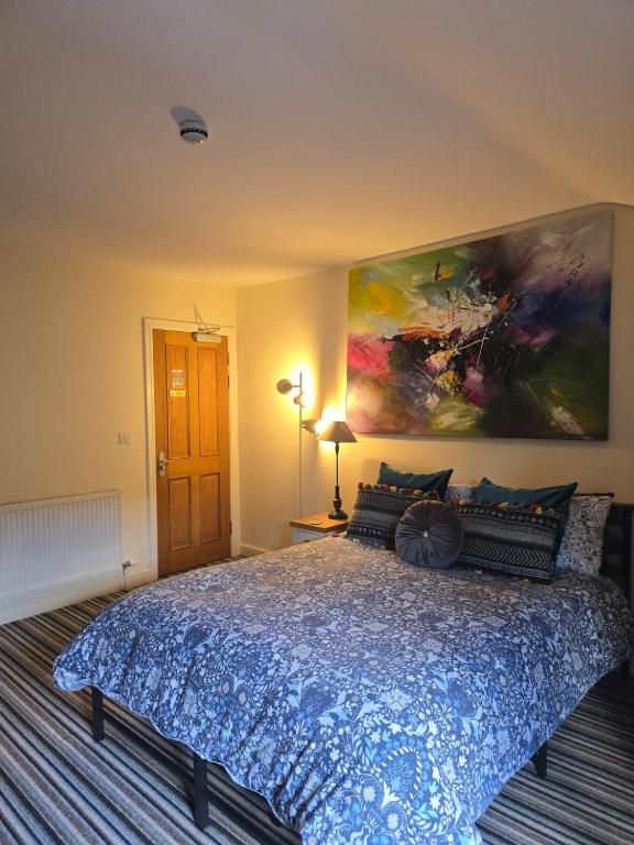 a bedroom with a large bed with a large painting on the wall at Honeymoon Suite - The Unicorn Hotel in Llanidloes