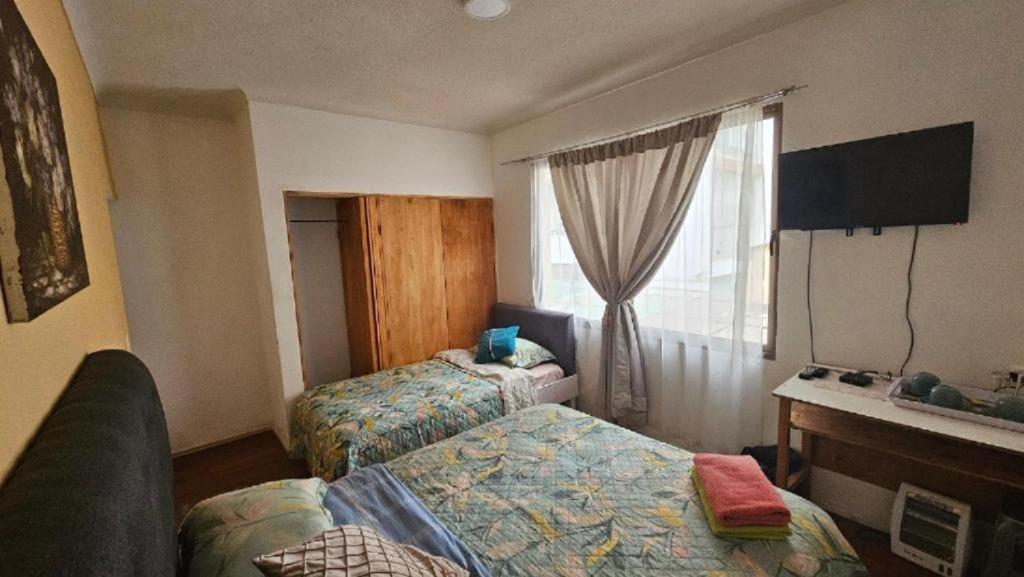 a hotel room with two beds and a window at Hostal Quintamar Viña del mar in Viña del Mar
