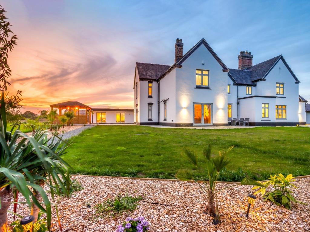 a white house with a sunset in the background at 7 Bed in Whitchurch 95835 in Prees