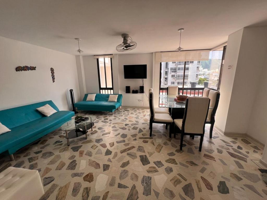 a living room with a blue couch and a table at Apartamento cerca a la playa en el rodadero in La Tigrera