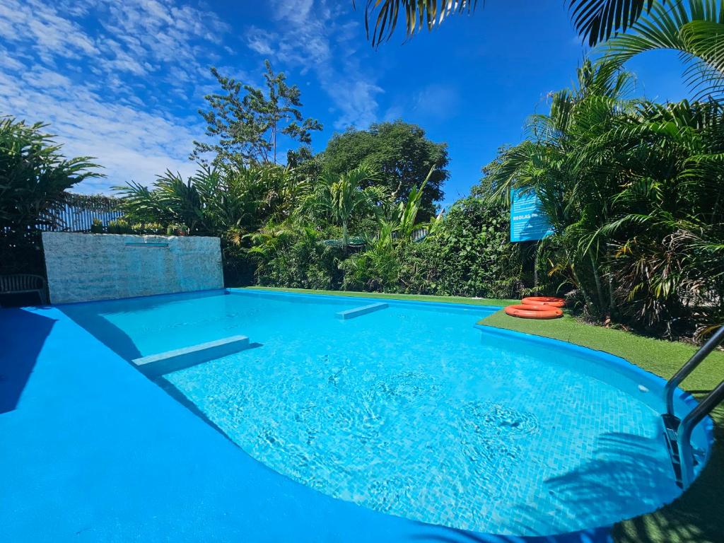 a blue swimming pool with trees in the background at Ballena Rey Hotel in Uvita