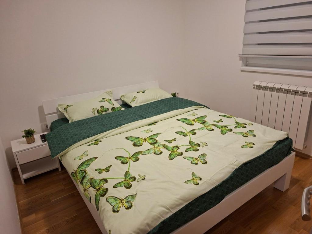 a bed with a green and white blanket on it at Stan na dan Ramonda in Donje Mladice