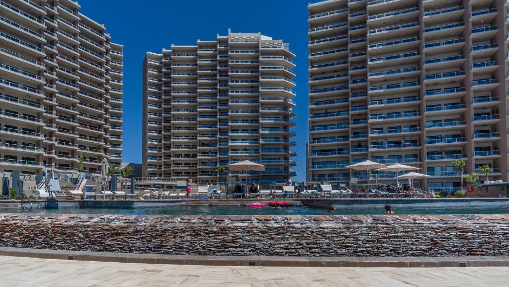 two tall buildings next to a beach with umbrellas at 2BR 2BA condo @ Las Palomas Cabrillo 804 in Puerto Peñasco