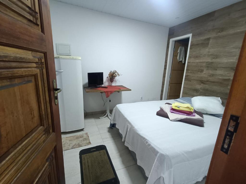 a bedroom with a bed and a desk with a computer at Suíte Privativa no Centro de Mangaratiba in Mangaratiba