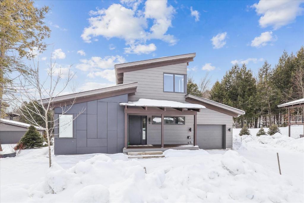 une maison avec un garage sous la neige dans l'établissement Streamside Lodge: 4 br, fireplace, sauna, game room, summer pool, à Stowe Fork