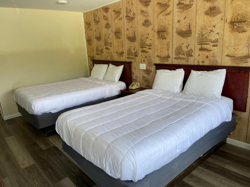 two beds in a hotel room with white sheets at Paramount Motel Pocono in East Stroudsburg