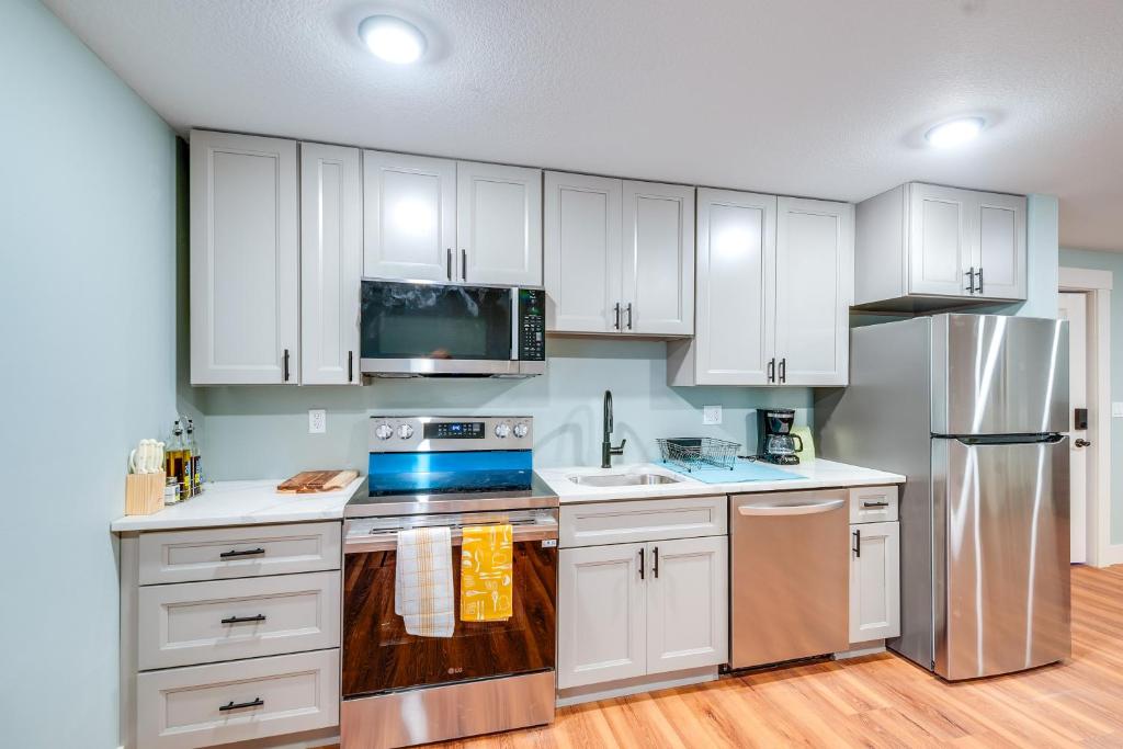 a kitchen with white cabinets and a stainless steel refrigerator at 4 Blocks to Riverwalk Updated Astoria Studio in Tongue Point Village