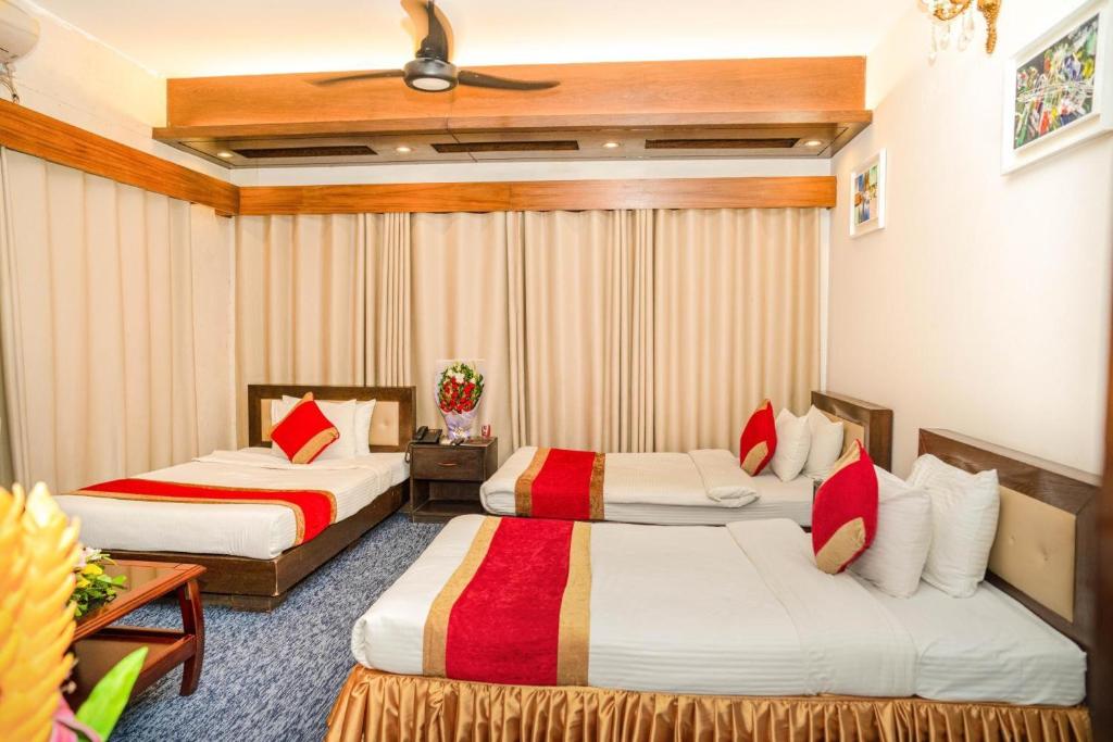 a hotel room with two beds and a table at The Air Inn Uttara in Dhaka