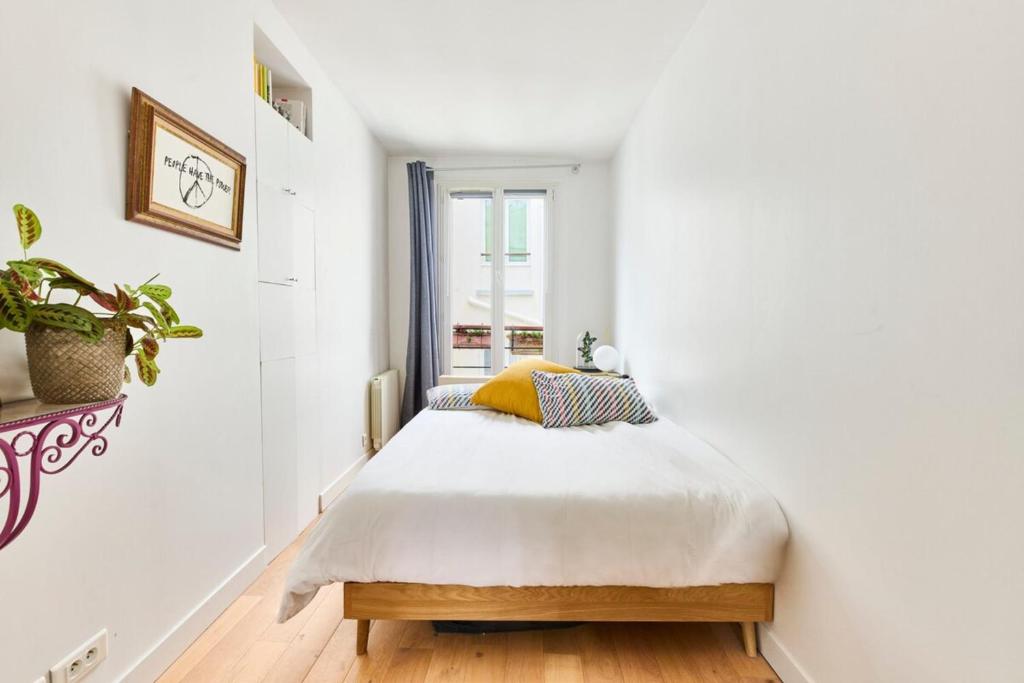 a bed in a white room with a window at Basilica of the Sacred Heart - Heart of Montmartre in Paris