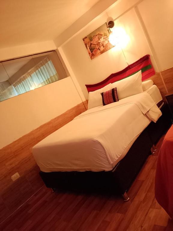 a bedroom with a large bed with white sheets and pillows at Inca Town In in Cusco