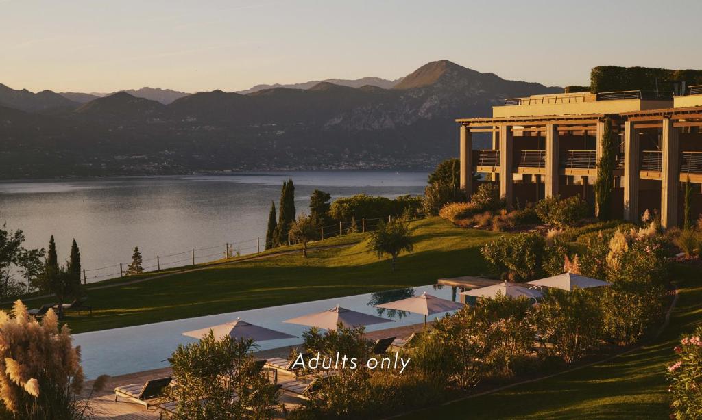 a view of a building with a lake and mountains at Cape of Senses in Torri del Benaco