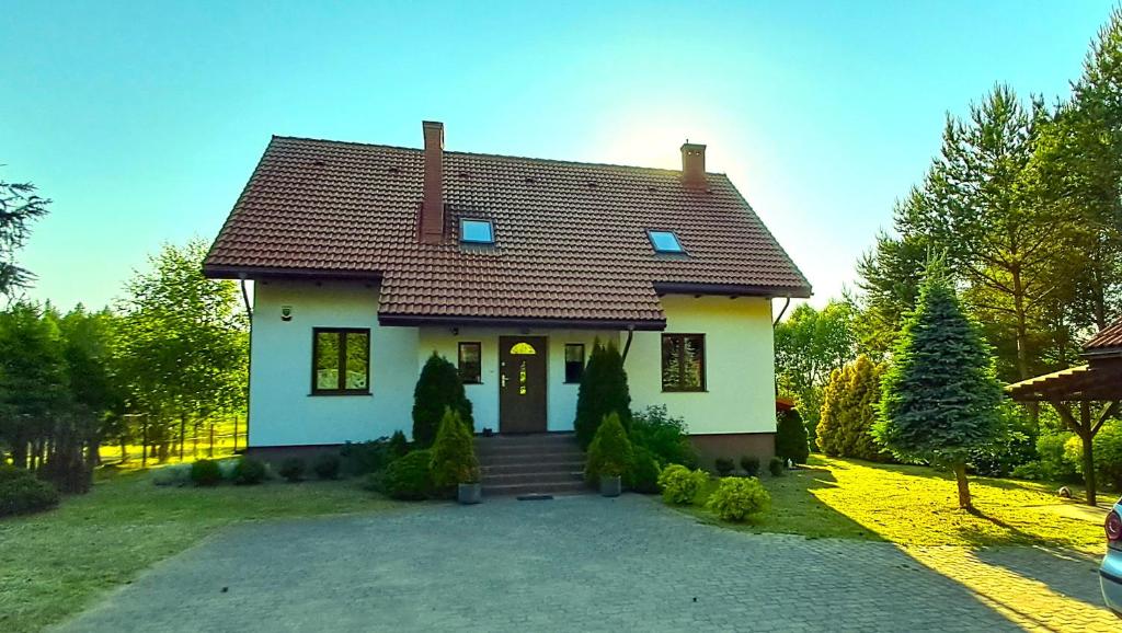 a small white house with a driveway at Dom nad Stawem Pokoje Gościnne 