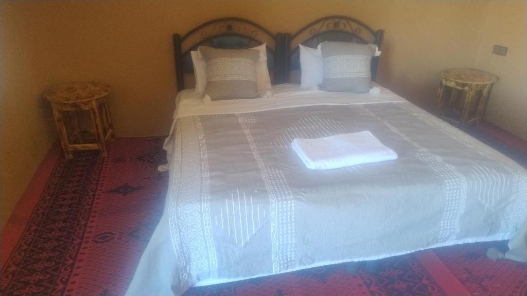 a bedroom with a large bed with white sheets and pillows at Mhamid Nomad Camp in Mhamid