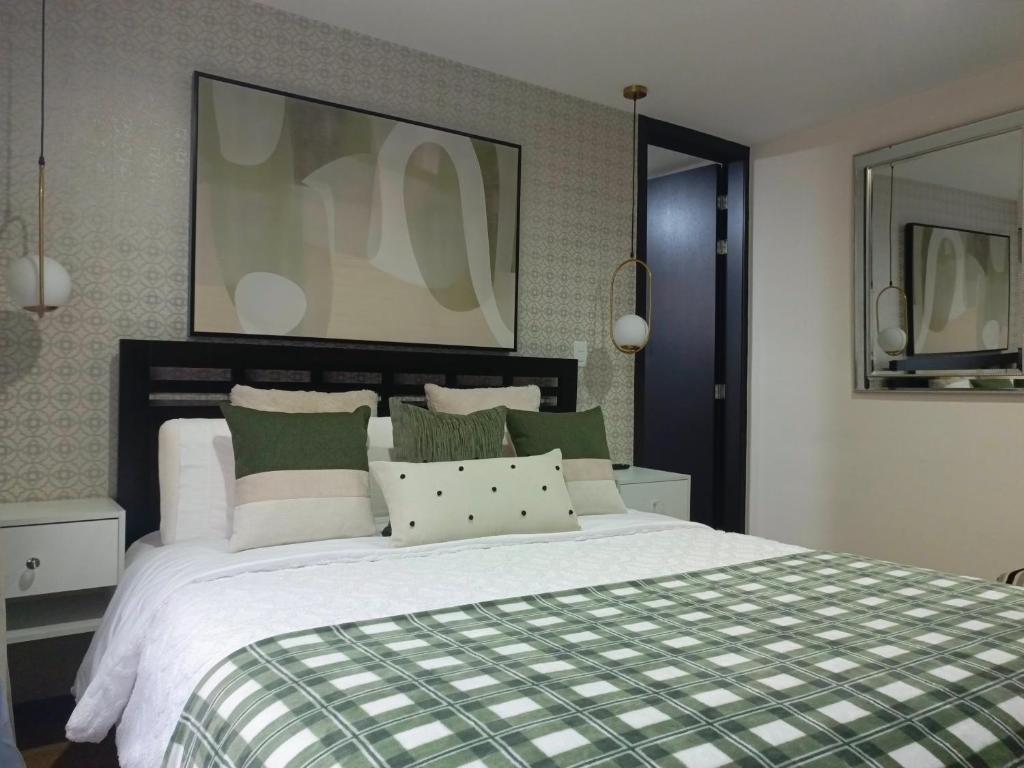a bedroom with a large bed with green and white pillows at Apartment - 2Bedrooms - QueenBed - Balcony - Parking - 7thFLOOR in Quito