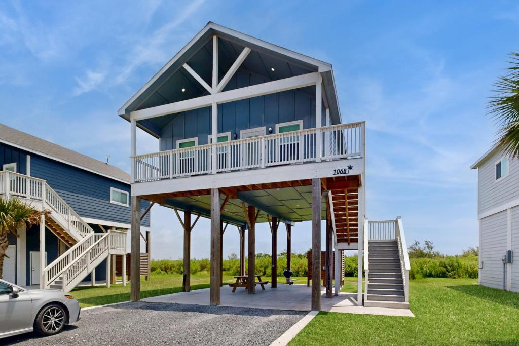 ein Haus mit einem Balkon und einem Auto vor dem Haus in der Unterkunft Modern Steps to Beach Shared Pool & Playground in Caplen