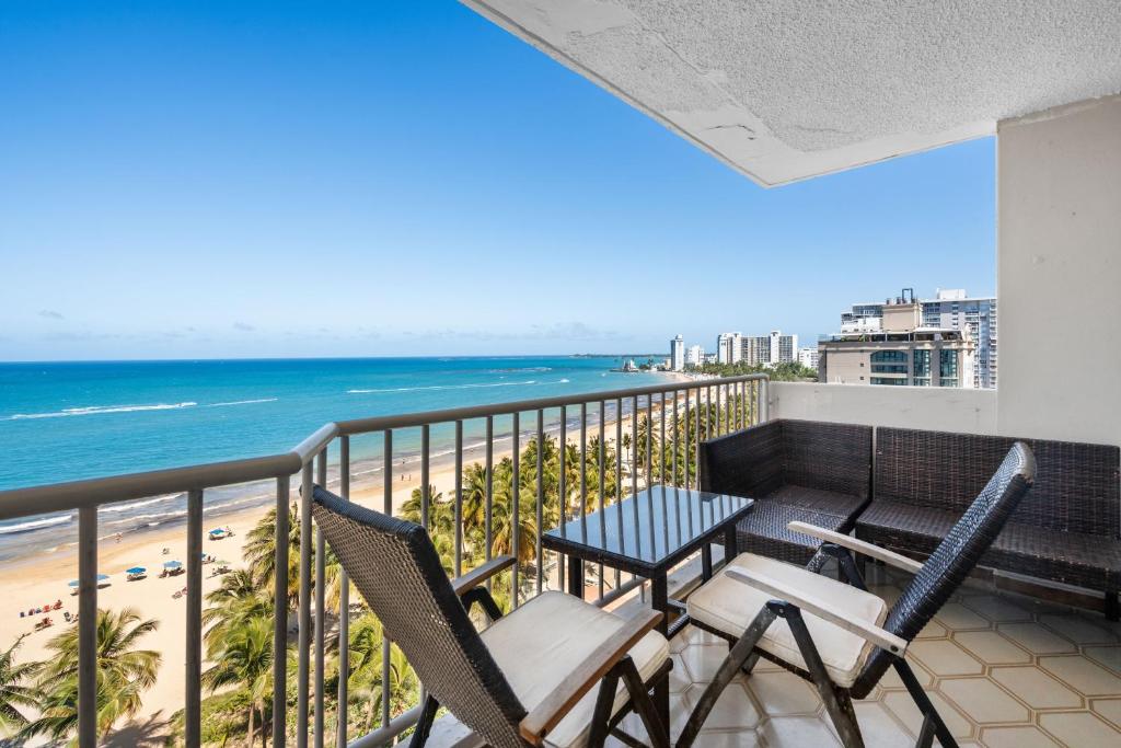 a balcony with chairs and a table and the beach at Oceanfront Terrace Communal Pool Ac in San Juan