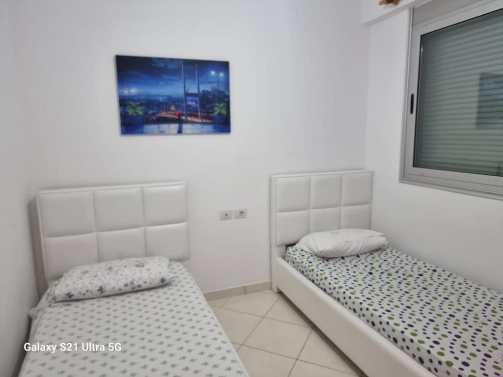 two twin beds in a room with a window at Luxury Two Bedrooms and two balcony beachfront apartment in Vlorë