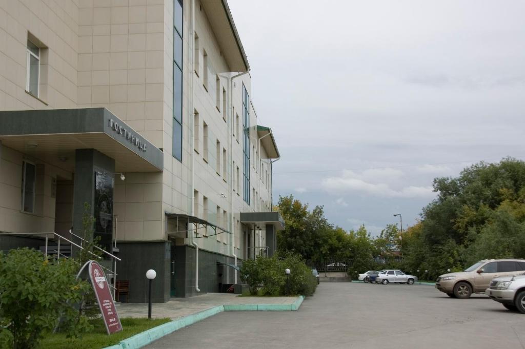 un bâtiment avec des voitures garées dans un parking dans l'établissement Hotel 55 Shirota, à Novossibirsk