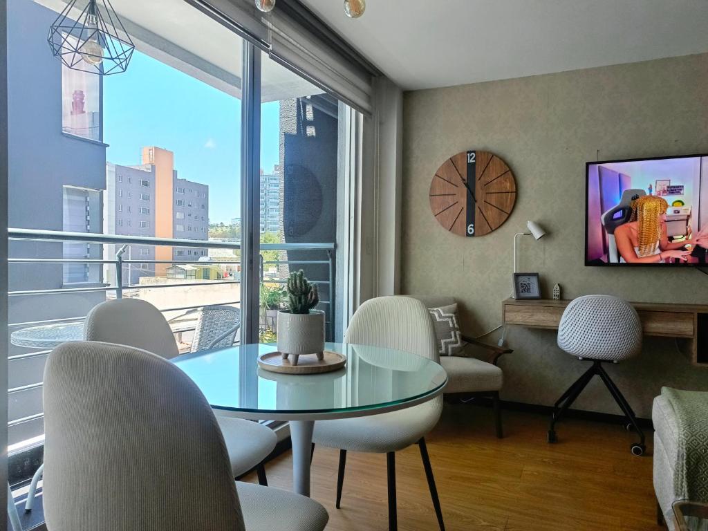a living room with a table and chairs and a clock at Like a Home - 2Bedrooms - QueenBed - Balcony - Parking - 7Th FLOOR in Quito