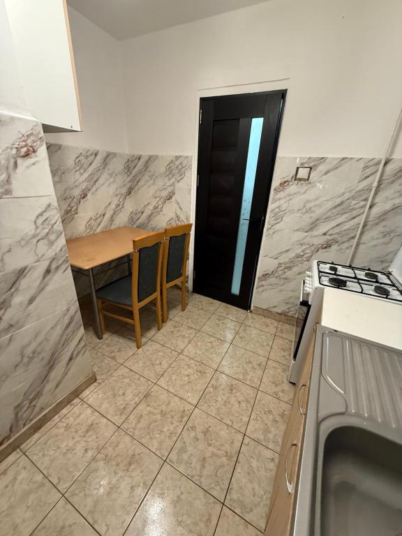 a kitchen with a door and a table and a chair at Apartament 2 camere in Craiova
