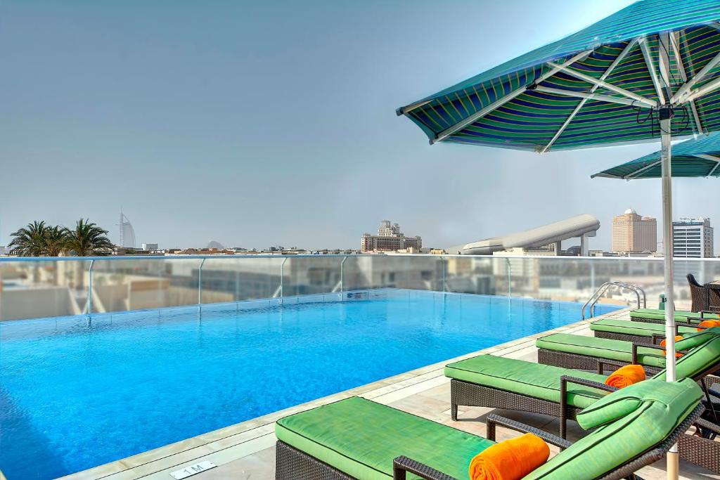a swimming pool with chairs and umbrellas on a building at Al Khoory Atrium in Dubai