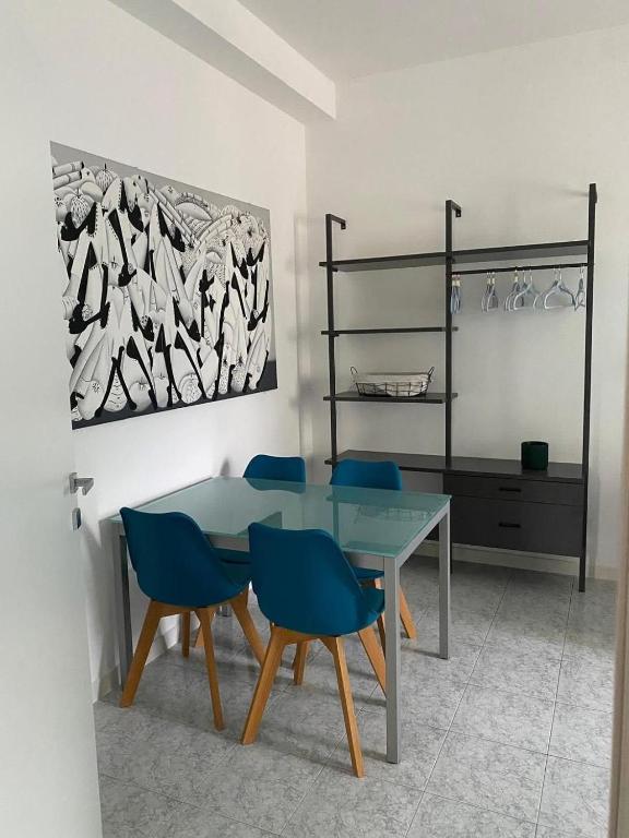 a dining room with a glass table and blue chairs at Pitia House in Rozzano
