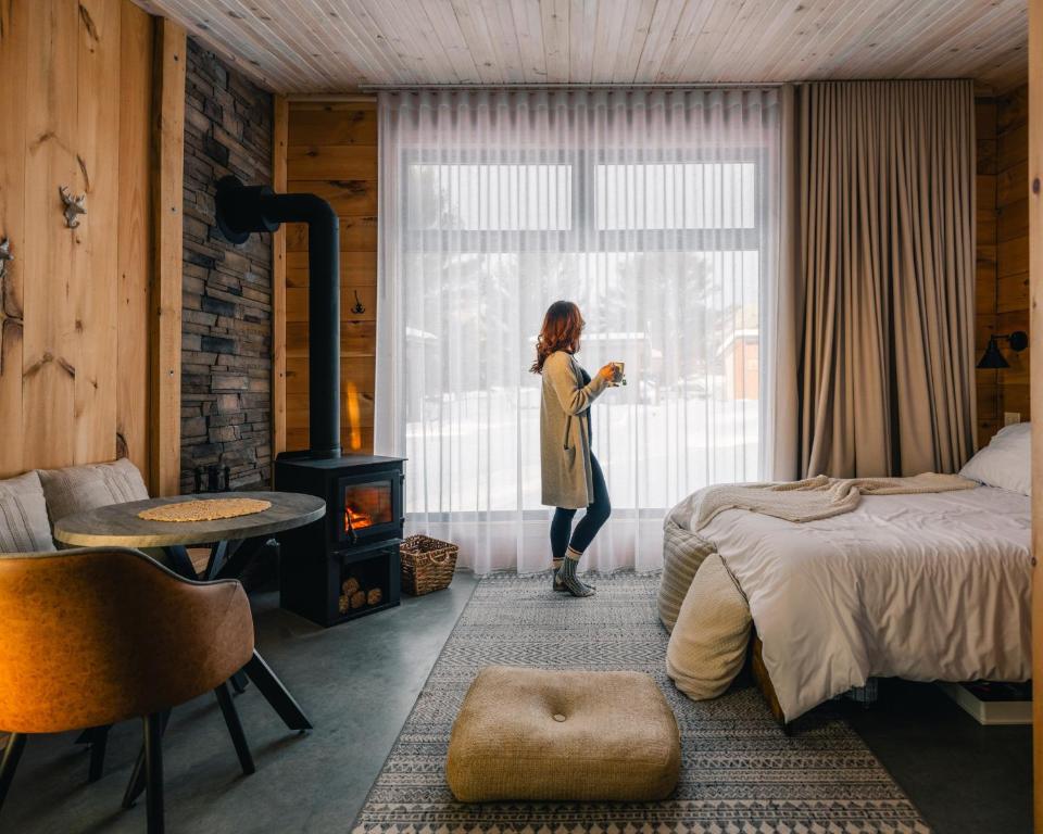 a woman standing in a bedroom looking out the window at Le 2800 du Parc in Shawinigan