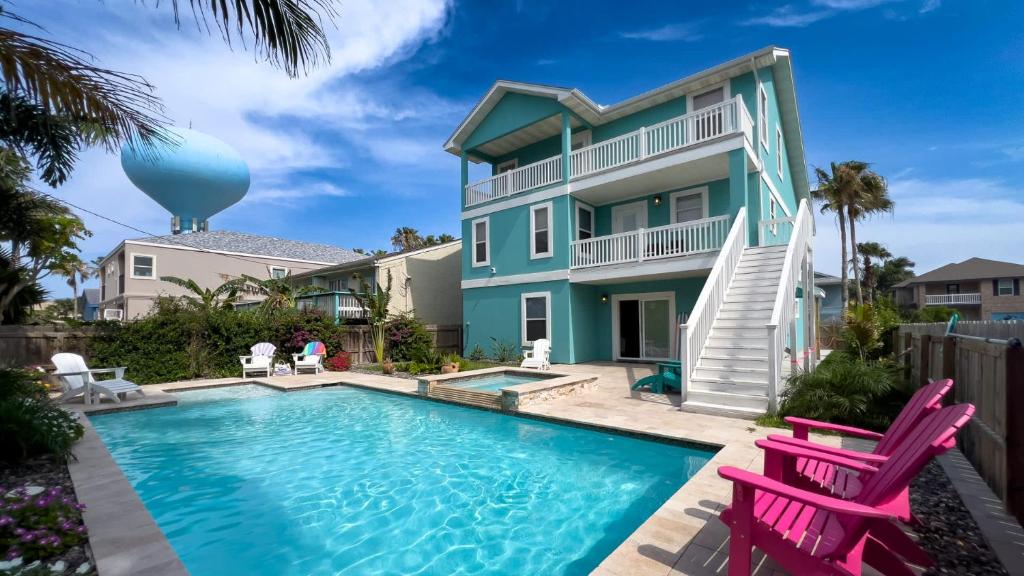 une maison avec une piscine et deux chaises roses dans l'établissement Upscale & Spacious Home Renovated Pool, à South Padre Island