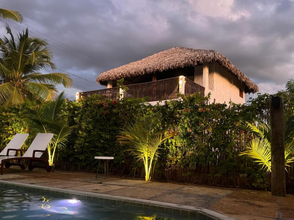 a house with a thatched roof next to a swimming pool at chale vilana in Atins