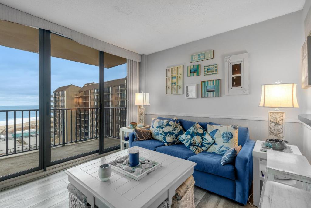 a living room with a blue couch and a large window at Sea Colony - 709 Brandywine House Rd in Bethany Beach