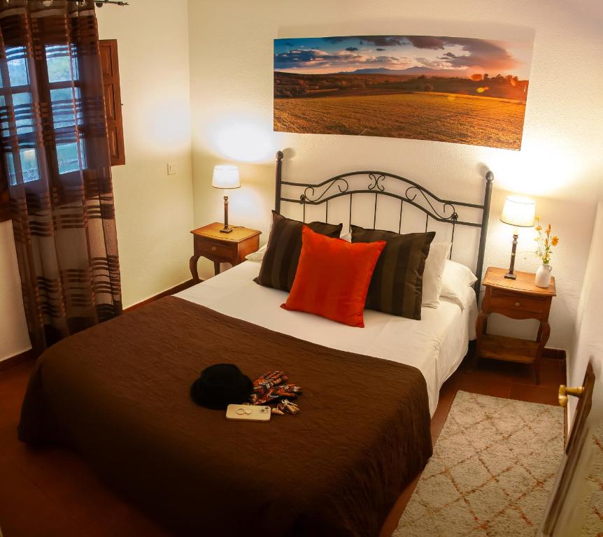 a bedroom with a bed with a black blanket and orange pillows at Al Viento, Alojamiento & Turismo Rural Prádena del Rincón in Prádena del Rincón