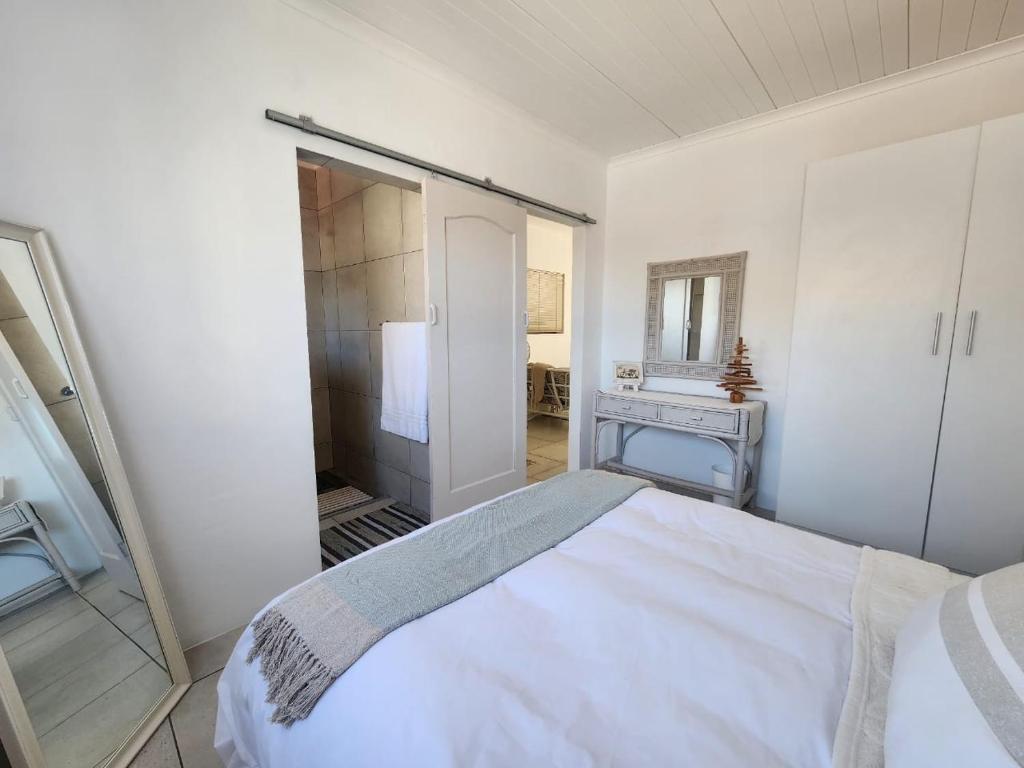 a white bedroom with a bed and a mirror at 87 on Sunbird B in Langebaan