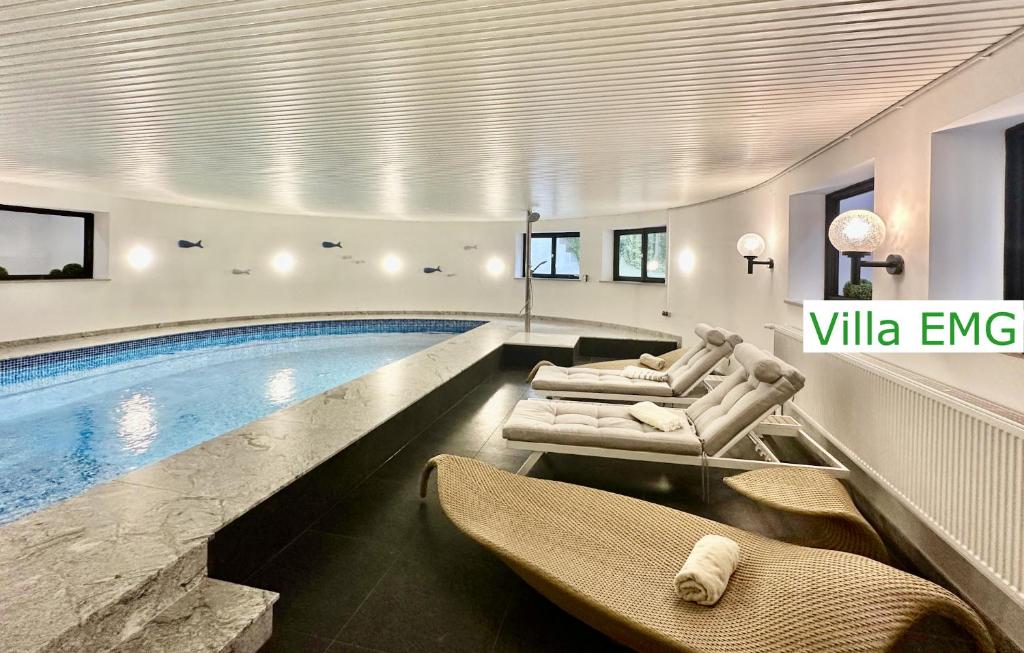 a swimming pool with two lounge chairs and a swimming pool at Luxury Holidays Villa EMG Munich with Forest and Lake - Moosburg an der Isar in Moosburg