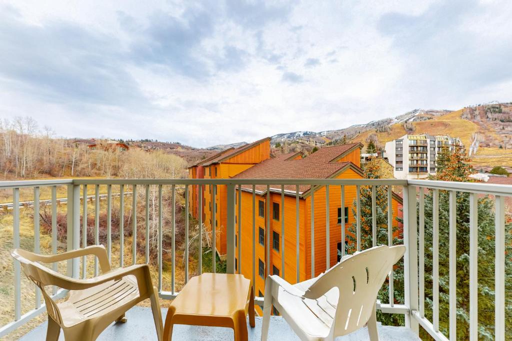 スティームボート・スプリングズにあるSki Time Square 516の椅子2脚とオレンジ色の家があるバルコニー