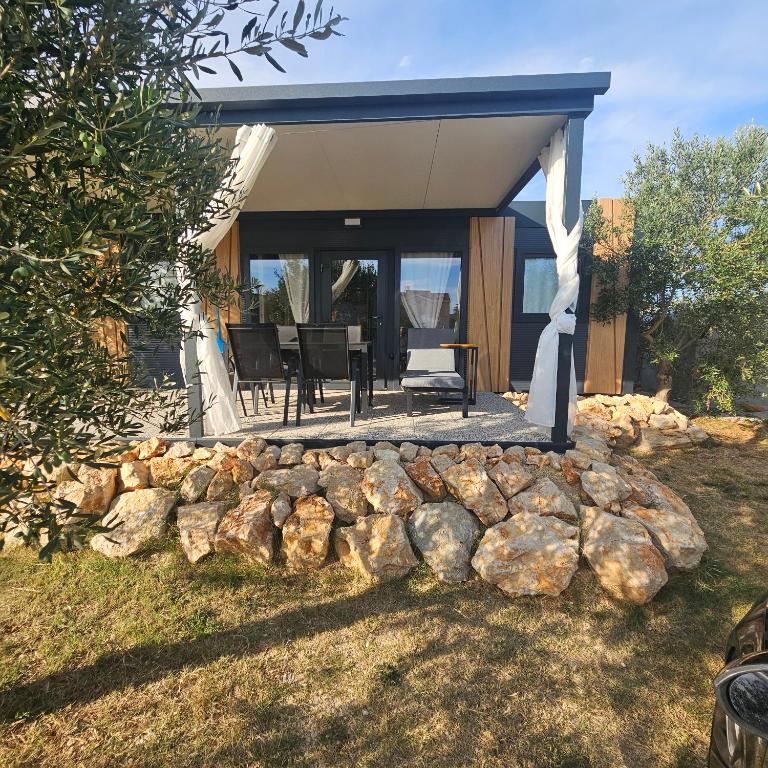 a home with a stone wall and a gazebo at Mobile home RIA in Privlaka