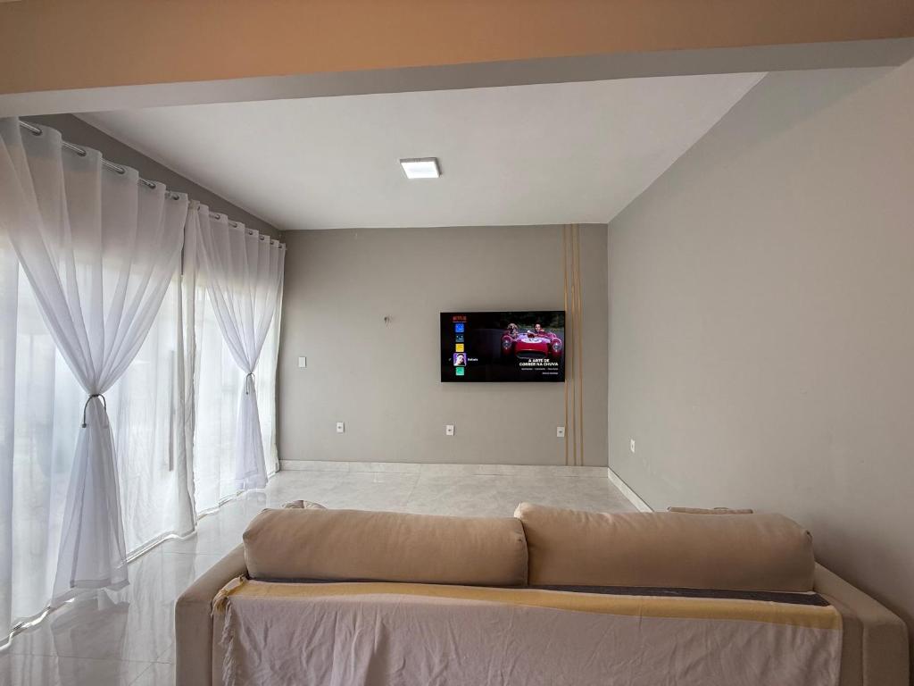 a living room with a couch and a tv on the wall at Alugo Casa COP30 em Belém no distrito de icoaraci in Belém