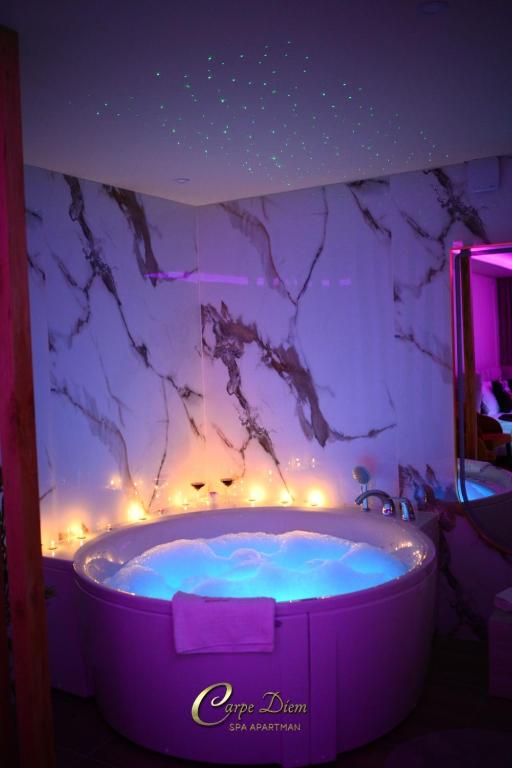 a purple tub in a bathroom with a marble wall at Carpe Diem Spa Apartman in Teslić