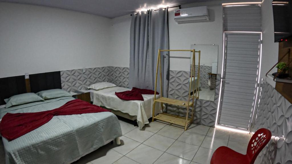 a bedroom with two beds and a red chair at viladowalbinhobarreirinhas in Barreirinhas