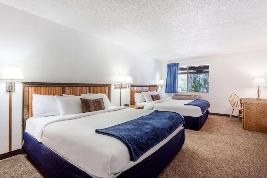 a hotel room with two beds and a desk at Sandpoint Inn in Ponderay