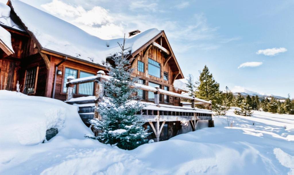 a log cabin in the snow with a tree at Antler Ridge Lodge in Big Sky