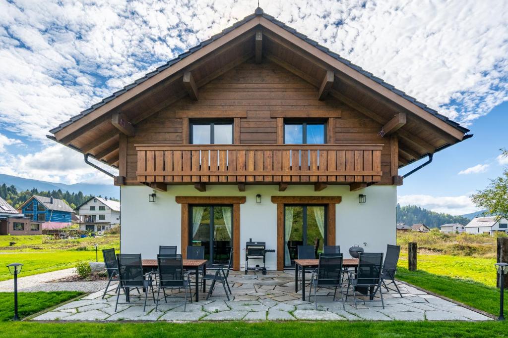Una casa de troncos con terraza, mesa y sillas. en Chalet Karolína, en Zuberec