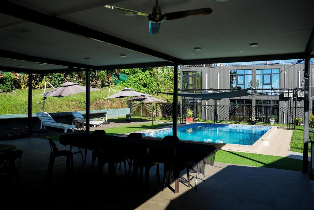 een huis met een zwembad met tafels en stoelen bij Hotel Laimoa in Apia