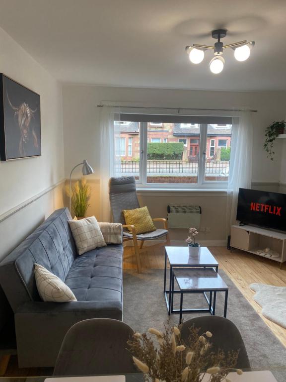 a living room with a blue couch and a table at Modern apartment in Glasgow West End, free parking in Scotstoun West Station
