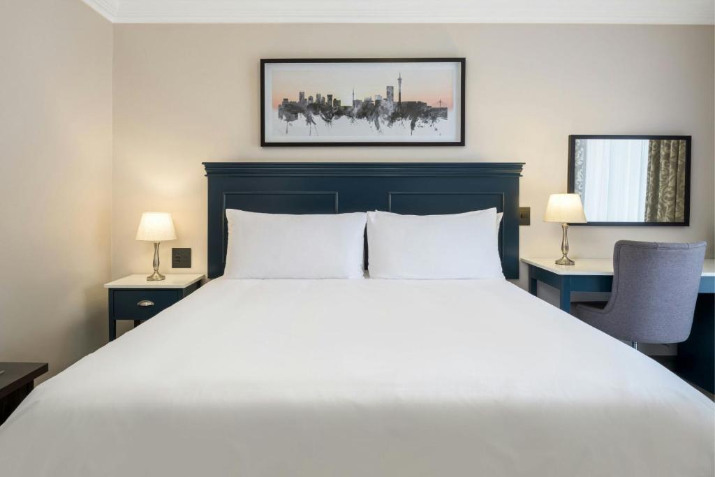 a bedroom with a large white bed and two lamps at Protea Hotel by Marriott Johannesburg Balalaika Sandton in Johannesburg