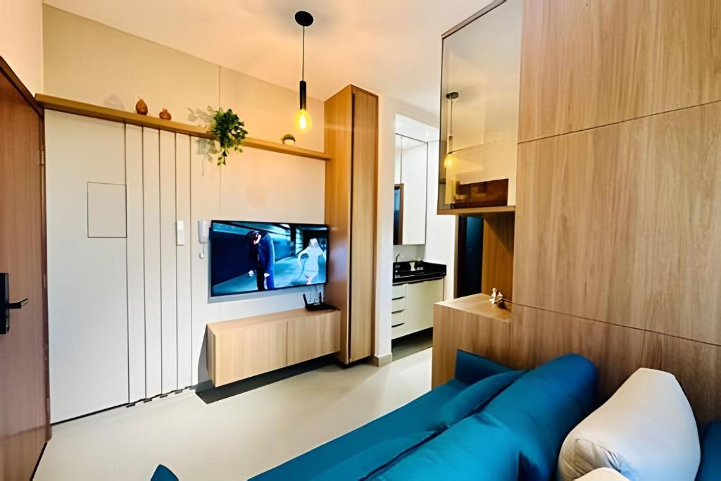 Una sala de estar con un sofá azul y un televisor en Studio New Home | Praticidade em um Só Lugar, en Uberlândia