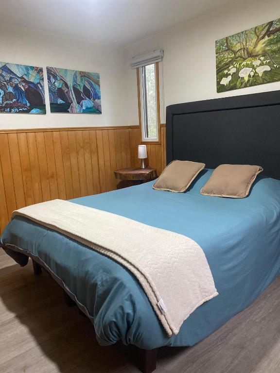 a bedroom with a blue bed with two pillows on it at Aldea Molco Arrayan in Villarrica