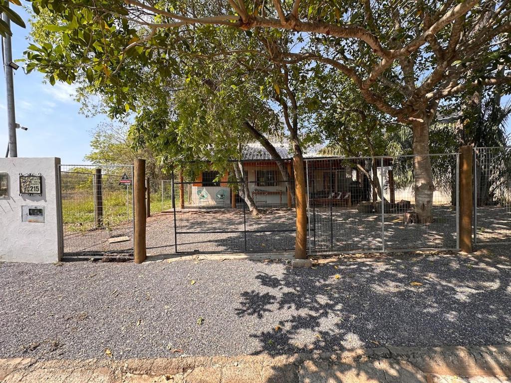 a fence with a tree in front of a park at Casa Das Árvores BonitoMS in Bonito