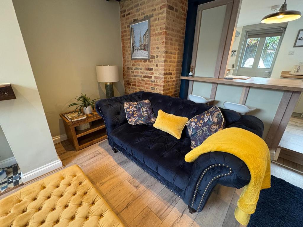 a living room with a black couch and a yellow blanket at Stylish Town House in Medieval Grid in Bury Saint Edmunds