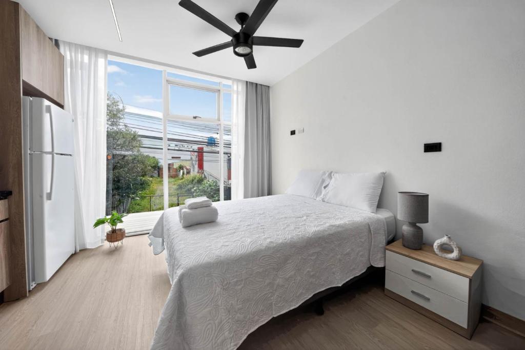 ein weißes Schlafzimmer mit einem Bett und einem großen Fenster in der Unterkunft Sabana Urbana in San José